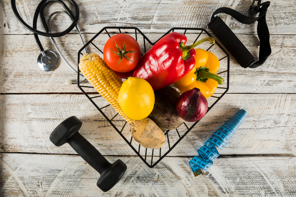 Fresh vegetables surrounded by fitness equipments; stethoscope and measuring tape